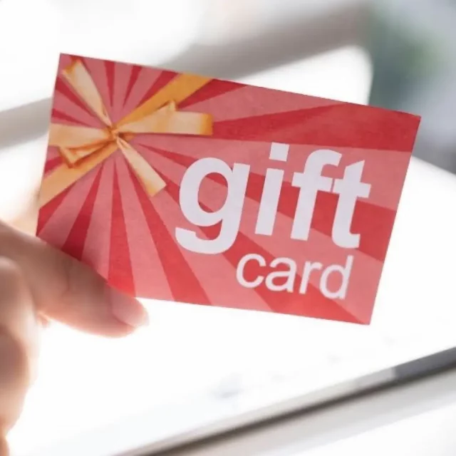 A hand holding up a red piece of paper that says "gift" card" in large type