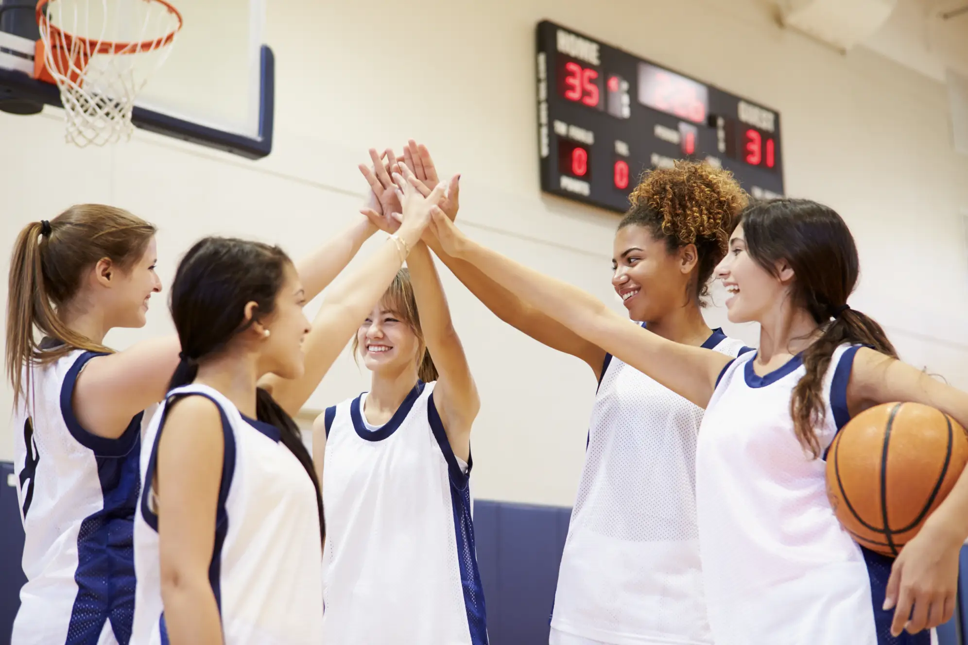 Group of girls playing basketball high-fiving and smiling