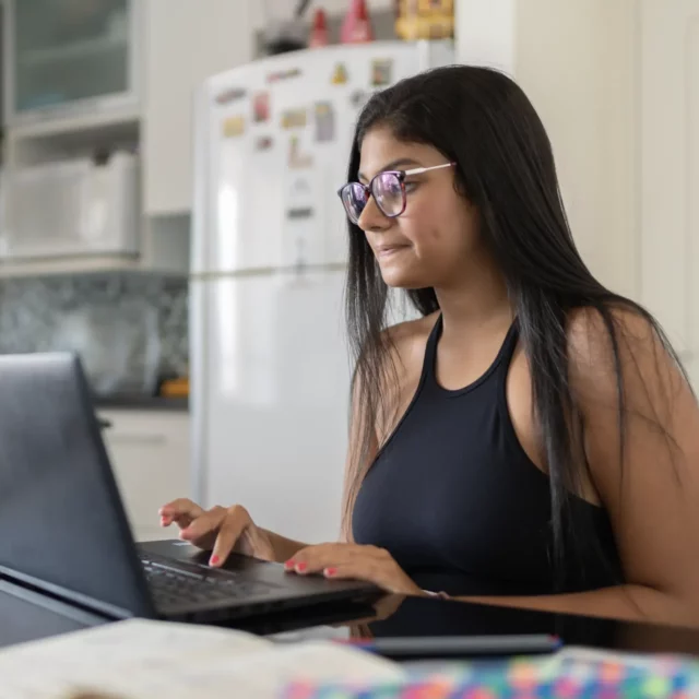 Young woman working at laptop at a kitchen table