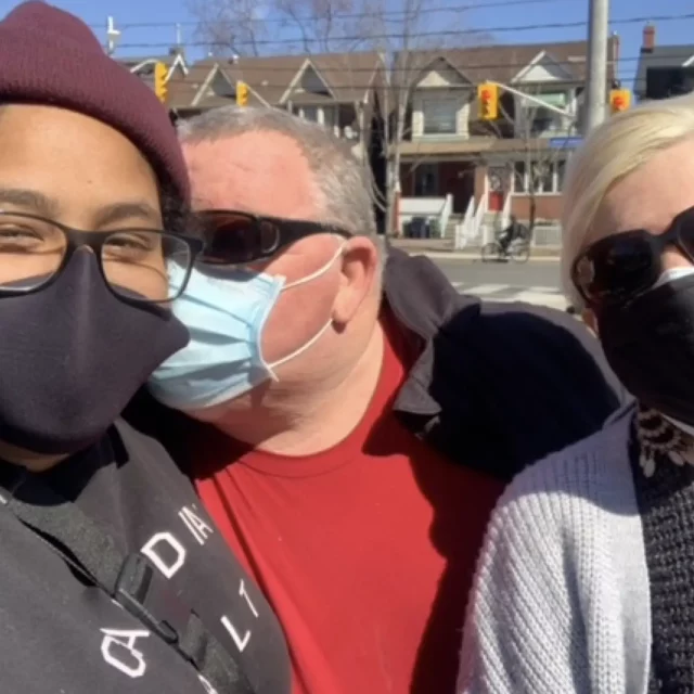 Three people outside in the sun with masks and glasses on taking a selfie