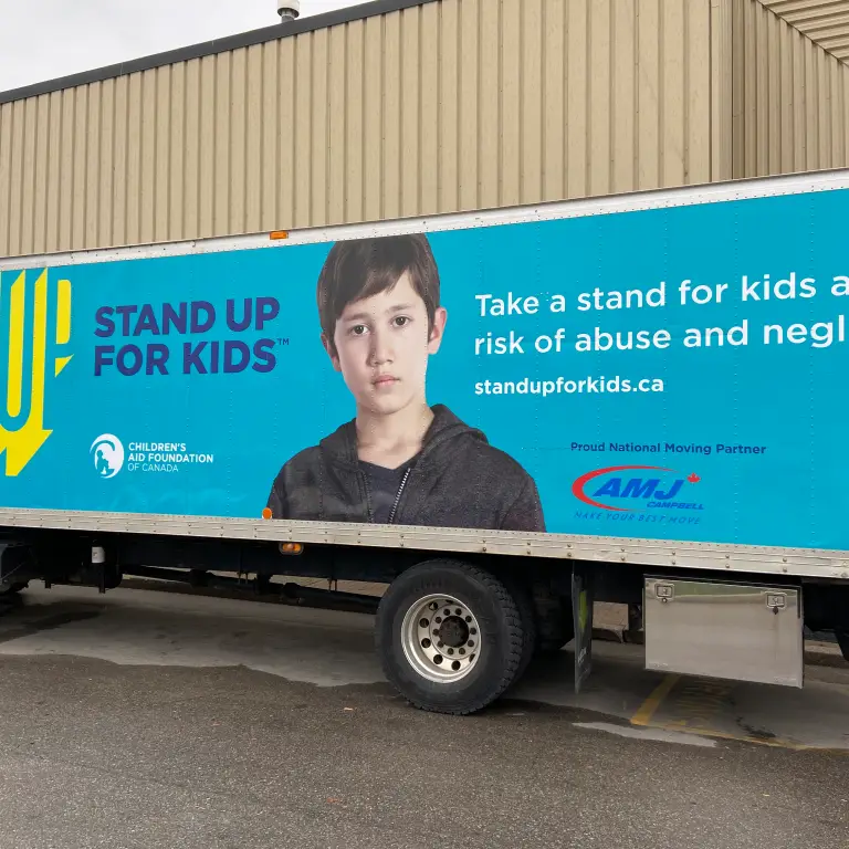 Stand Up for Kids advertisement on the side of a transport truck featuring a child in the centre