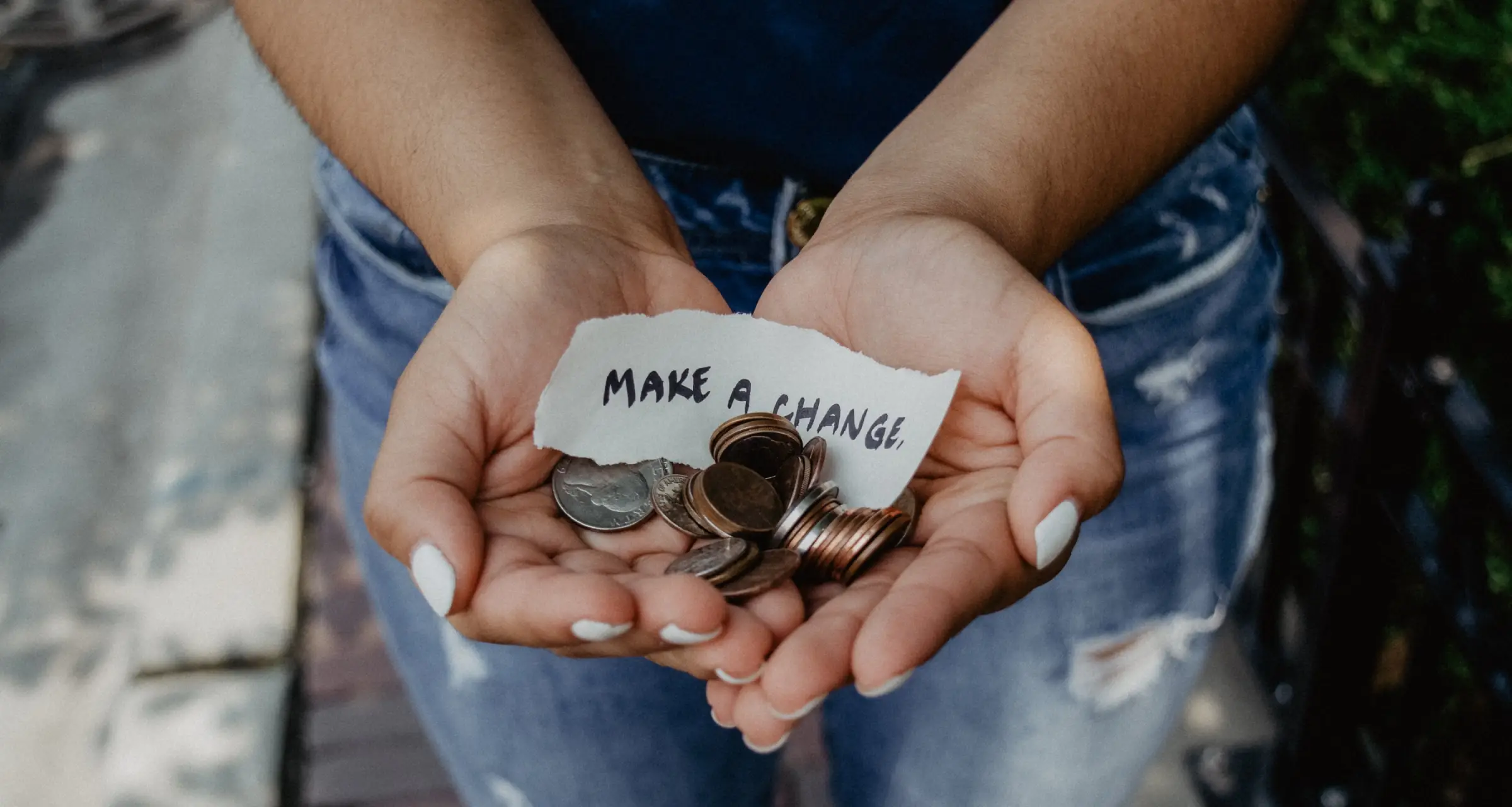Hands holding coins with a piece of paper that says make a change