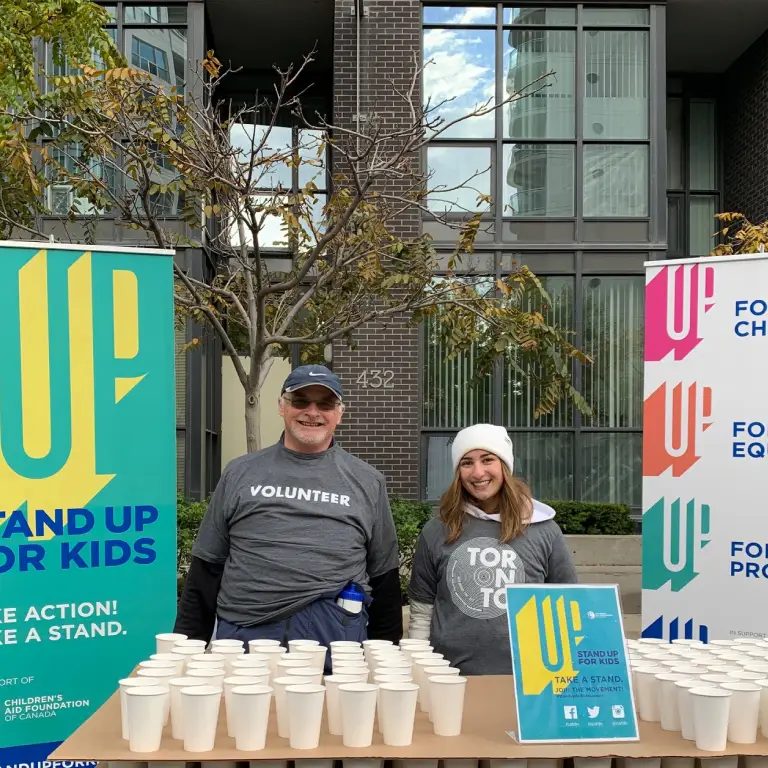 Two volunteers standing behind a table covered with cups