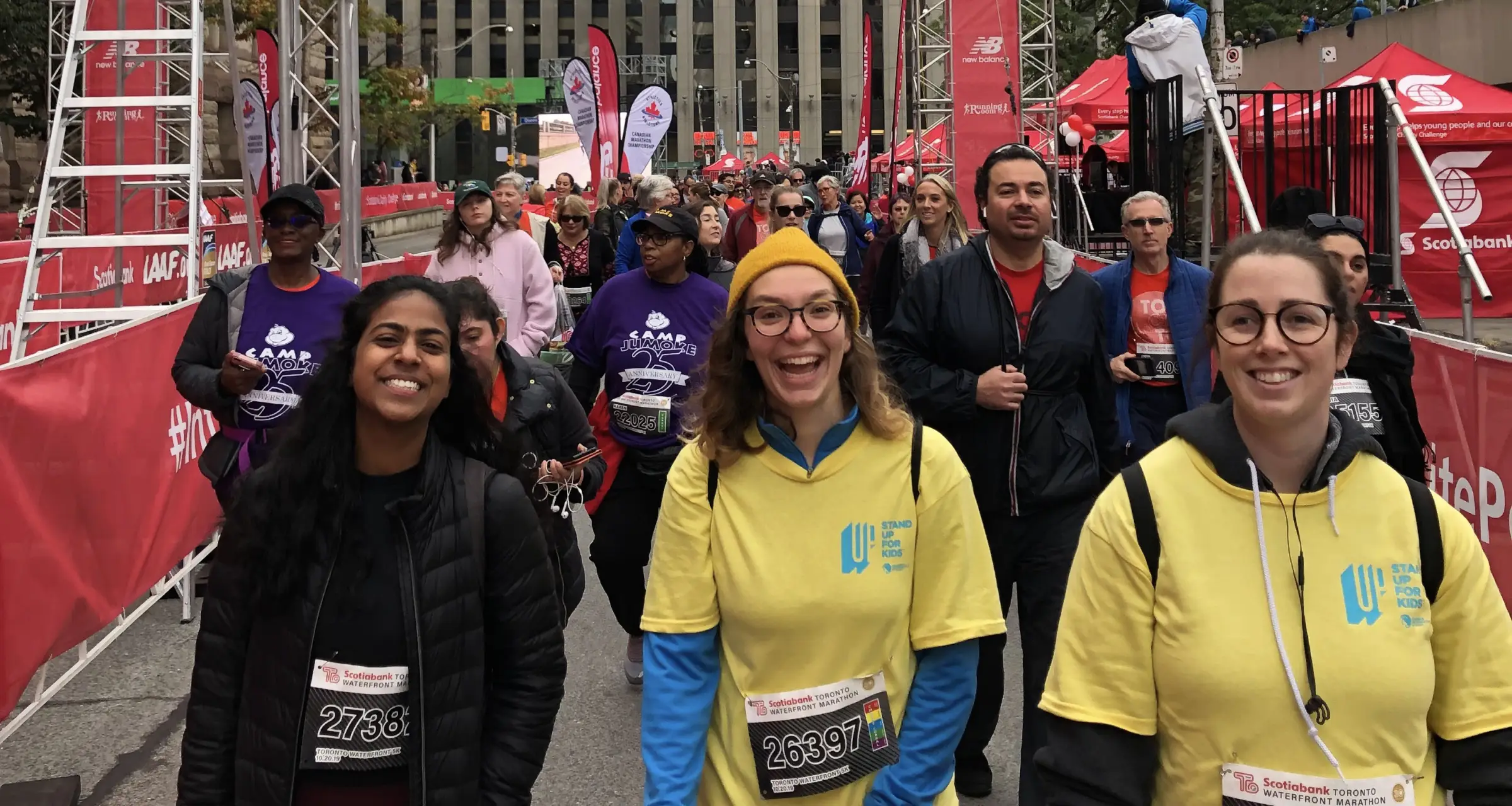 Group of people at a walk smiling and wearing number plates