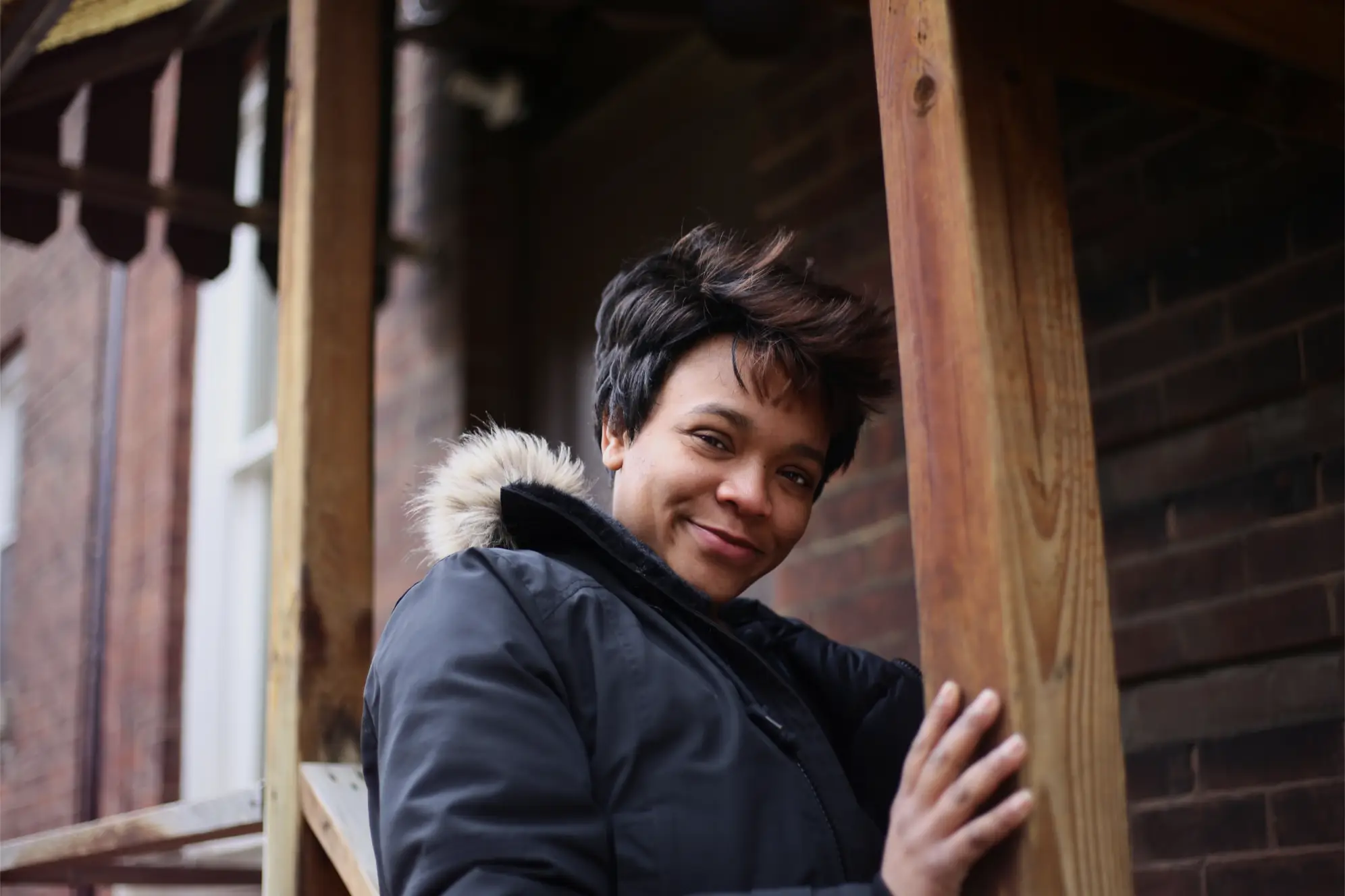 Young woman in winter jacket with short brown hair smiling down at the camera