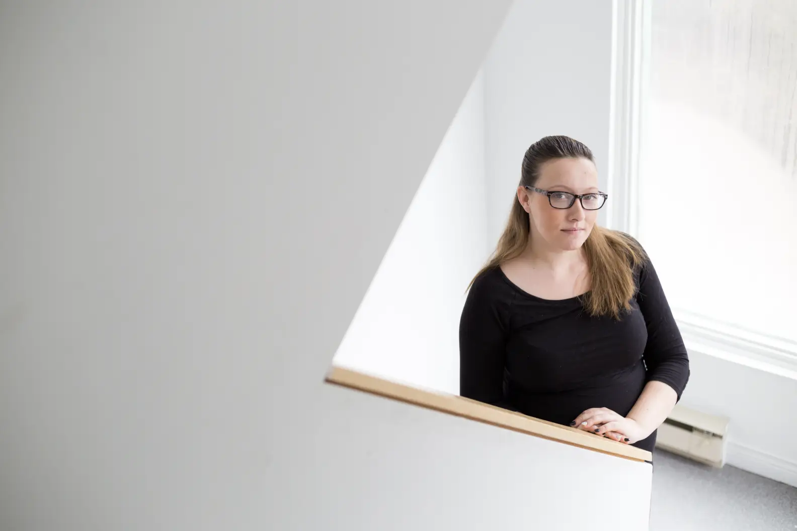 Woman wearing glasses on white staircase in front of window