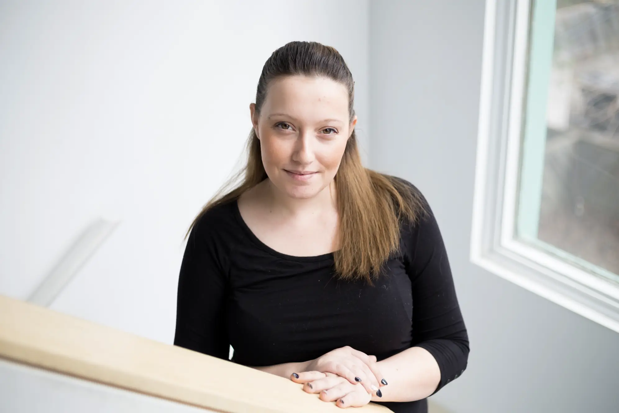 Woman standing on white staircase wearing black shirt and smiling