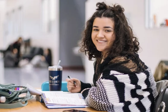 Young person in striped sweater sitting at table and smiling at the camera