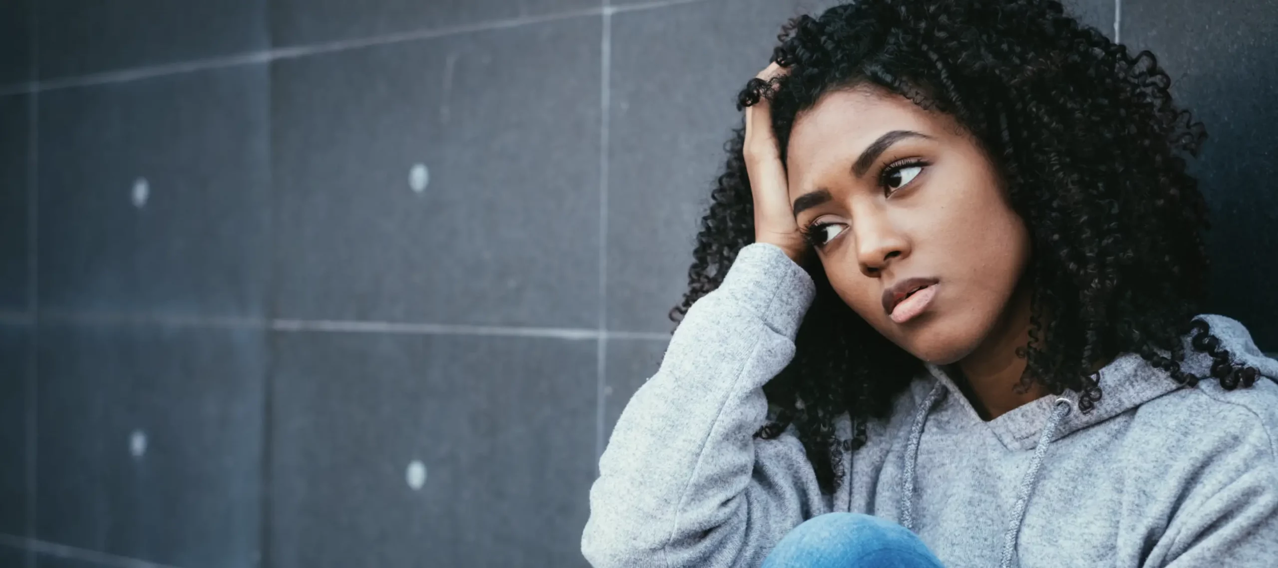 Young woman sitting with head in hand with upset look on her face